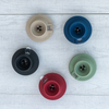 A collection of five switch bases in different colors (black, blue, beige, green, and red) displayed on a wooden surface.